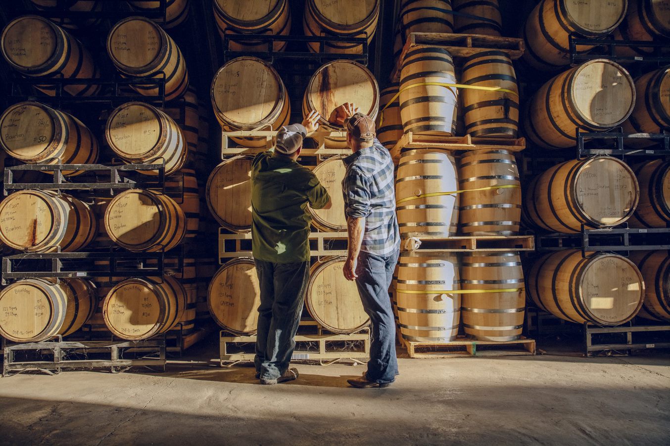 men looking at aging barrels